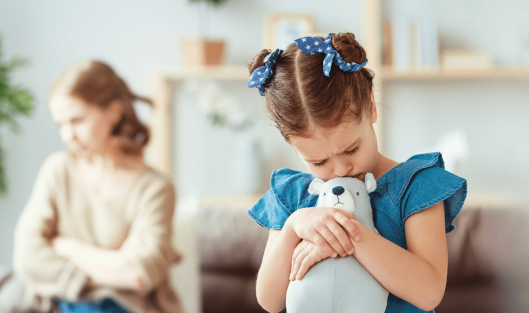 woman sitting on a couch distant from her child going through coercive control